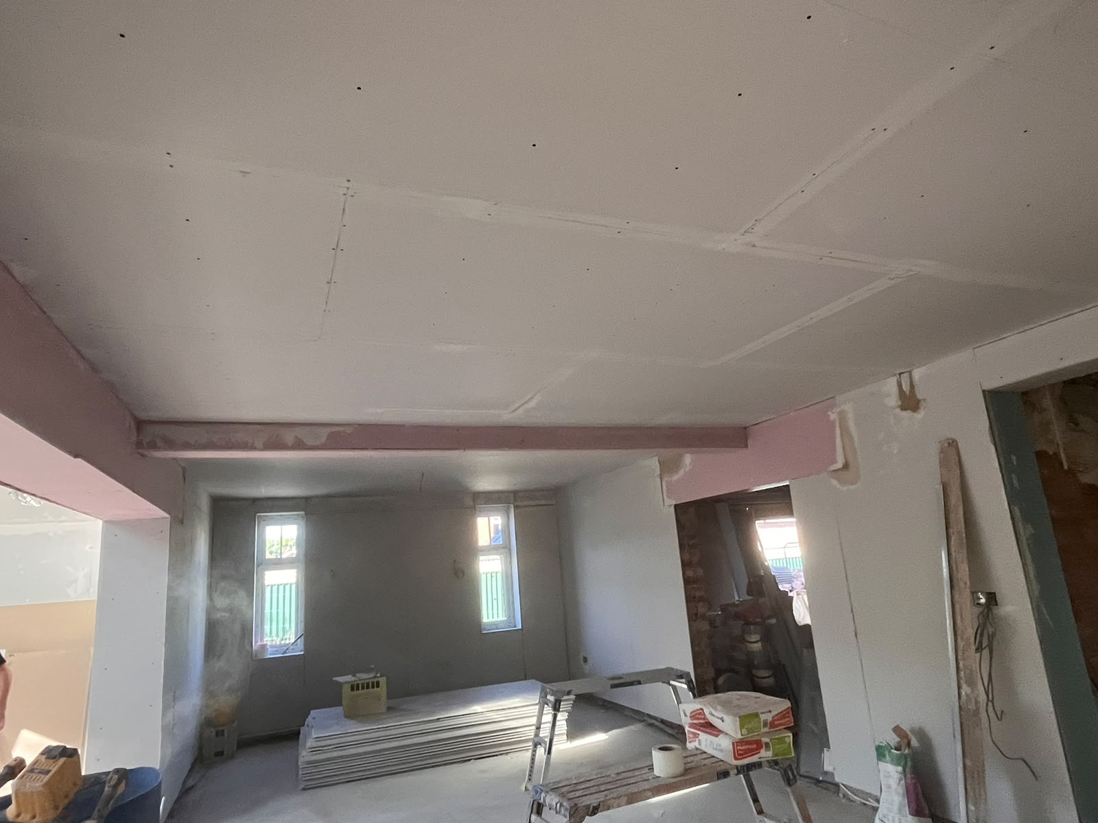 Plasterboard lining on a ceiling and walls, boards stacked on the floor